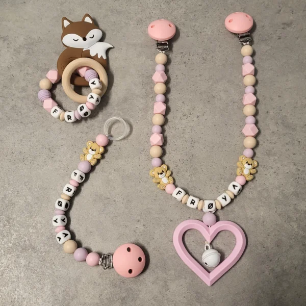 Personlig gavesett til baby med vognlenke, bitering og smokkelenke i babyrosa, beige og duse farger.